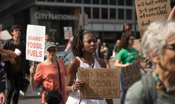 a woman holds a sign in protest of fossil fuels