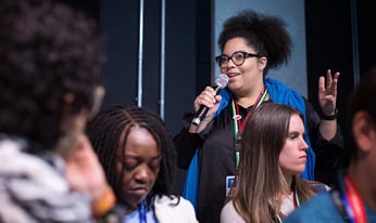 a woman with a microphone speaks to a crowd