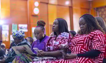 women seated during a meeting, taking notes
