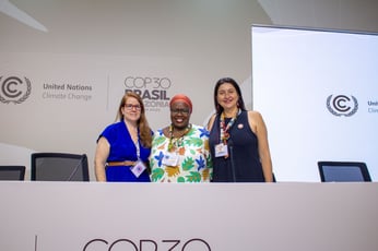 Three individuals standing behind a podium at a COP31 press conference.